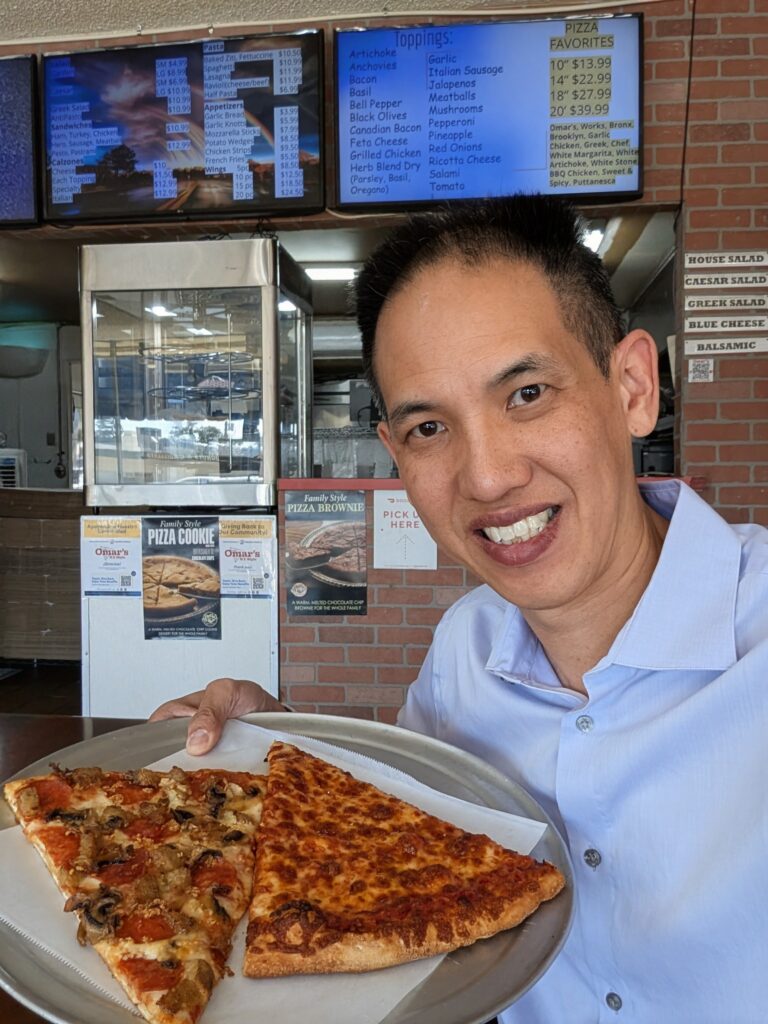 Dr Kwan holding slices of pizza at Omar's Pizza Arcadia
