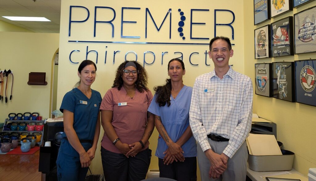 Premier Massage & Chiropractic team of four standing in front of the PREMIER wall